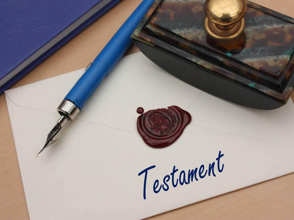 Füllfederhalter mit versiegeltem Umschlag mit der Aufschrift „Testament“ auf einem Schreibtisch.
